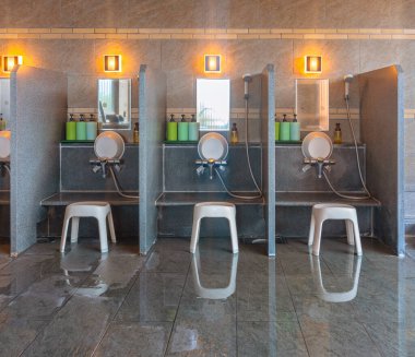 Geleneksel Japon ev içi onsen kaplıcası Furo-isu plastik banyo sandalyeleri, duş muslukları ya da musluklar ve karan kovaları ile tamamlanır..