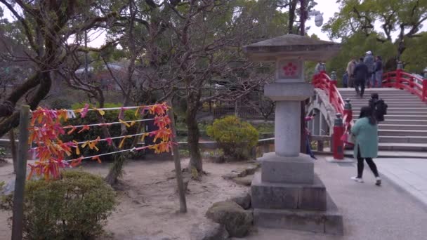 2022年12月7日 日本九州 展示亚洲游客漫步在大泽佛神神社一座红太子桥上的视频 旁边是一个绑着木村纸片的木村 — 图库视频影像
