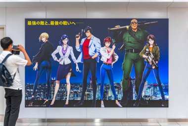 Tokyo, Japonya - Bölüm 08 2023: Bir yaya Shinjuku İstasyonu 'nda, Manga Şehri Avcısı Nicky Larson' dan uyarlanan Japon anime melek tozunun tüm karakterlerini tasvir eden bir posterin fotoğrafını çeker..