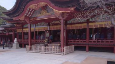 kyushu, fukuoka - 07 Aralık 2022: Dazaifu Tapınağı 'ndaki Şinto onur salonunu yakalayan eğik video turistler koridor boyunca dua ederken tipik karahafu kıvrımlı sazdan çatısını vurguluyor.