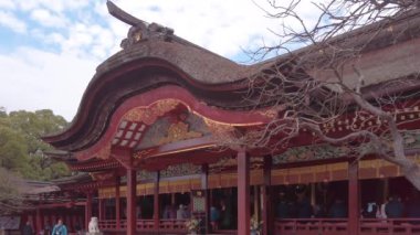 kyushu, fukuoka - 07 Aralık 2022: Dazaifu Tapınağı 'ndaki Şinto onur salonunun turistler koridorda dua ederken kendine özgü kıvrımlı sazdan çatısını gösteren eğik videosu.