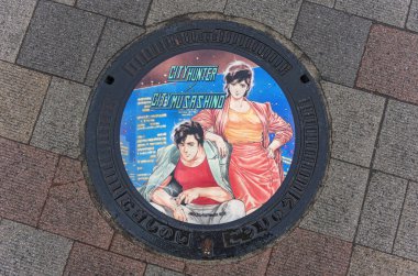 tokyo, japan - apr 25 2024: Wet manhole illustrated with the heroes of the Japanese manga and TV series City Hunter or Nicky Larson illustrated by Tsukasa Hojo for the City of Musashino in Kichijoji. clipart