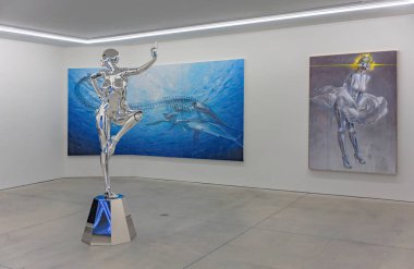 tokyo, harajuku - may 10 2023: Chrome statue of a female gynoid by Japanese artist Hajime Sorayama in front of large canvas paintings of Jurassic Pangaea and Marilyn Monroe in Nanzuka Art gallery. clipart