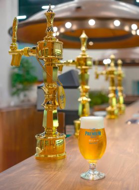 Tokyo, fuchu mar 26 2024: Bir bar tezgahında bir lale bardağı Japon birası bir kenara altın bira motorları Suntory Tokyo-Musashino Bira Fabrikası 'nın barında bedava tur sırasında erişilebilir.