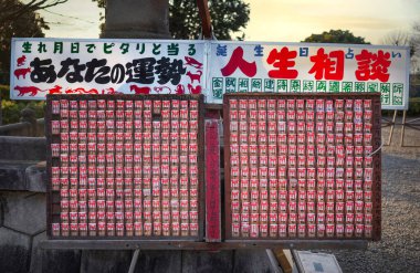 tokyo, musashikoyama - febr 23 2024: Shelf of Japanese Buddhist votive strips sold as birthday horoscopes and life advice based on zodiac signs promising fortune predictions in Ikegami Honmonji Temple clipart