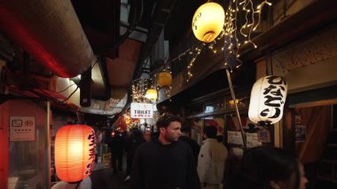 Tokyo, shinjuku - 13 Ocak 2025: Shinjuku Omoide Yokocho 'da Japon fenerleri ve neon ışıklarıyla aydınlatılmış dar bir sokak arasında hareketli bir gece sahnesi, canlı bir atmosferde küçük yiyecekler.