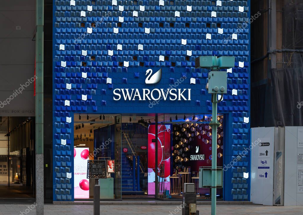 Tokyo, ginza - jan 08 2024: Swarovski Ginza store featuring a striking blue facade with glowing geometric patterns and a prominent swan logo, attracting shoppers with its luxurious crystal products.