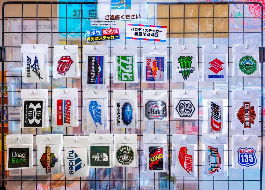 Japan, tokyo - march 25 2025: Waterproof and removable Japanese parody stickers of famous worldwide brand logos are displayed on a grid in a shop, appealing to tourists and locals for their humor.