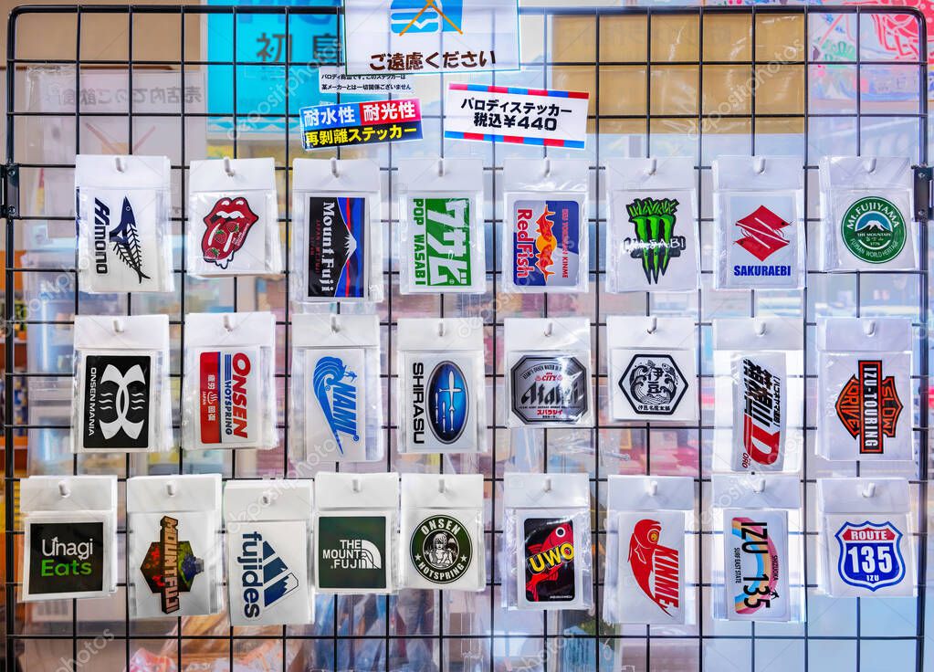 Japan, tokyo - march 25 2025: Waterproof and removable Japanese parody stickers of famous worldwide brand logos are displayed on a grid in a shop, appealing to tourists and locals for their humor.