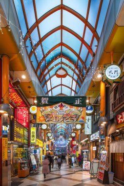 Tokyo, Nakano - Ocak 08 2025: Nakano kaplı alışveriş caddesini aydınlatan Japon Yeni Yıl dekorasyonları, festival afişleri ve neon tabelalar kemerli cam çatının altında gezinen müşterilerin üzerinde asılı.