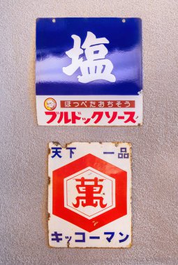 osaka, umeda - Aralık 05 2024: Boğa-Köpek Tuzu ve Kikkoman Soya Sosu için paslanmış Japon mineli tabelaları, Showa döneminde duvarda kullanılan retro yazı tipi yazı ve logotleri sergiliyor..