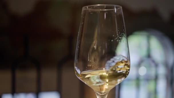 暗い背景にガラスの中で金の白ワインを振って ワインのコマーシャルのための美しいストック映像 ゴブレット内でワインの混合プロセスのビデオを閉じます スローモーション — ストック動画