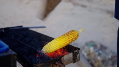 Yangında mısır pişirmek, yakın çekim, Mans 'ın elleri ateşin üzerinde mısır koçanı tutuyor, yağla kayganlaştırıyor. Ağır çekim. Yüksek kalite 4k görüntü