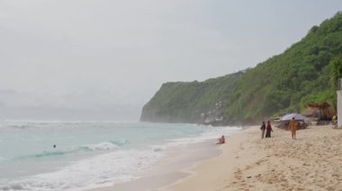 Okyanus kıyısı, kumlu sahilde bir tekne duruyor, sahildeki evin merdivenlerini görebilirsiniz. Ağır çekim, Bali..