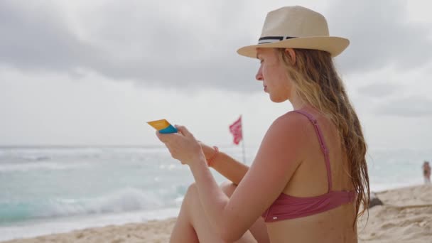 Una Joven Con Traje Baño Sombrero Paja Está Sentada Playa — Vídeo de stock