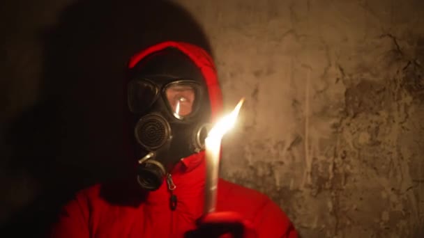 乌克兰战争 庇护所 一个戴防毒面具和防护服的男人躲在防空洞里 一个男人点燃蜡烛 他很害怕 高质量的 — 图库视频影像