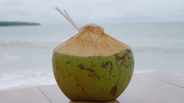 美しい紺碧の海の岸に近い視点から若いココナッツの新鮮なカクテル スローモーション — ストック動画