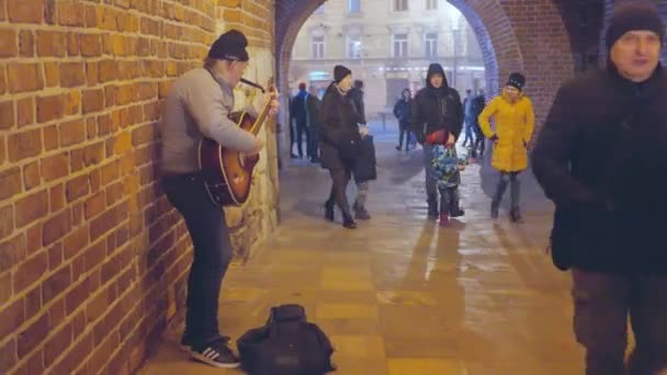 모자를 음악가가 저녁에 골목에서 기타를 연주하며 행인들에게 기부를 Warsaw January — 비디오