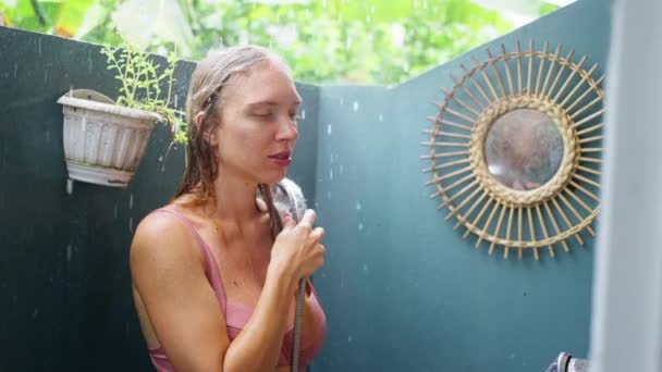 白化病妇女 站在露天淋浴间里 穿着粉色泳衣的女孩 在外面的雨 享受着对比淋浴间 慢动作 高质量的4K镜头 — 图库视频影像