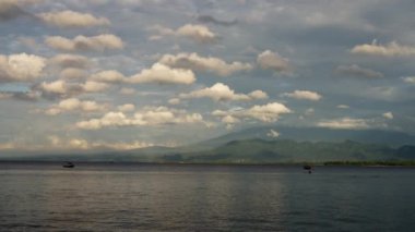 Mavi okyanus dalgaları ve inanılmaz gökyüzü, ayrıca dağlar. Gili Adası, Endonezya. Ağır çekim. Yüksek kalite 4k görüntü