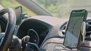 4K kullanan bir adamla arabada GPS navigasyonu. Seyrüsefer ekranına yaklaş, takip edilecek yolu göster. Akıllı telefon navigasyon cihazı. Google Maps. Akıllı telefondaki GPS navigasyon haritasını kapat