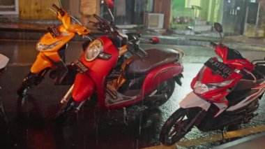 Bali 'nin gece sokağında yağmurda ıslak scooterlar fenerlerle aydınlatılıyor. Şehir tabelalarının ışığı yağmur sırasında geceleri sokakları aydınlatır. Yağmurlu gece, yüksek kalite
