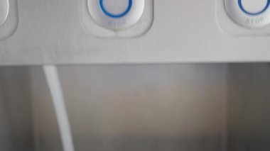 Bir adam umumi tuvalette lavabo kullanıyor, bir elin yakın çekimi su tedarik düğmesine basıyor, bir adam ellerini tuvalette lavabonun üzerinde yıkıyor. Yüksek kalite 4k görüntü