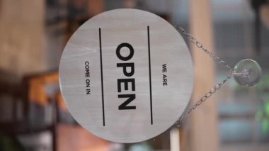 Açık yazılı bir tabela, cam kapıya asılı, kafenin girişi, yakın çekim. Dikey oryantasyon. 4K 'da yüksek kalite atış.