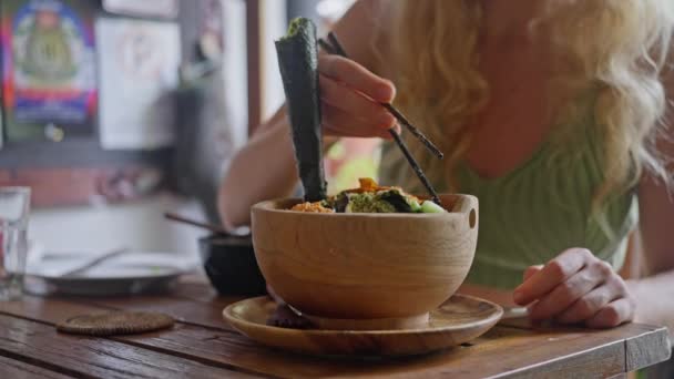 中国の箸で食べる女性 オーガニックで清潔な食事 ダイエットランチで新鮮な野菜 アボカドとサラダ キュウリ オリーブ 木製のプレートで 健康的な食べ物 スローモーション — ストック動画