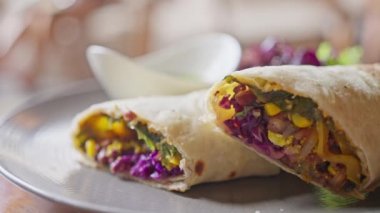 Vejetaryen yemeği, Pita ekmeğine sarılmış sebzeler. Mısır, lahana, yanında da avokado bazlı yeşil soslu bir fincan tabağı. Kapatın. Ağır çekim. Yüksek kalite 4k görüntü