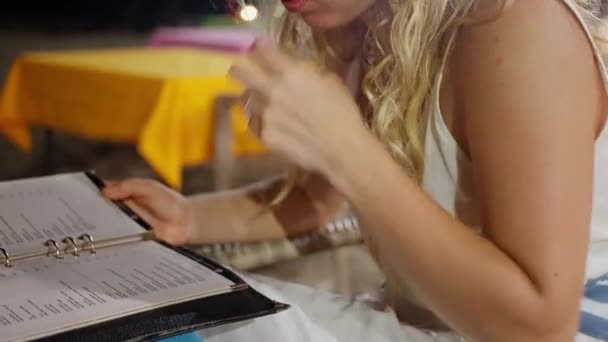 Blondynka Nocą Kawiarni Nad Oceanem Spogląda Menu Restauracji Wybiera Danie — Wideo stockowe