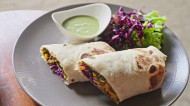 Sebze, mısır, lahanaya sarılmış pide. Yanında avokado bazlı yeşil soslu bir fincan tabağı var. Shawarma. Ağır çekim. Yüksek kalite 4k görüntü