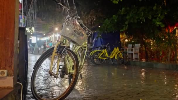 复古的黄色自行车与自行车袋 夜间在雨中湿透 晚上在自行车停车场大雨倾盆 黄色的自行车站在街上的雨中 高质量4K — 图库视频影像