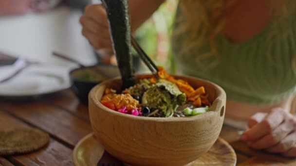 女人用中国筷子吃饭 有机和清洁的饮食 节食午餐吃新鲜蔬菜 色拉与鳄梨 诺莉海藻 在木制盘子 健康食品 慢动作 — 图库视频影像