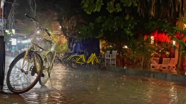 复古的黄色自行车与自行车袋 夜间在雨中湿透 晚上在自行车停车场大雨倾盆 黄色的自行车站在街上的雨中 高质量4K — 图库视频影像