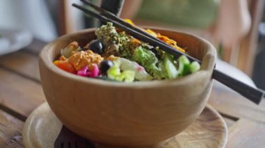 Geleneksel oryantal, Balili, vegan salatası, açık kırsal arka planda ahşap bir tabakta servis ediliyor. Yan görünüş. Yavaş çekim
