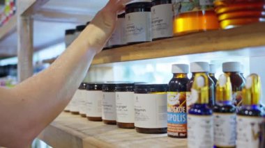 Eko-mağazadaki bir kadın aromatik yağlar, doğal kozmetik ürünleri ve arıcılık ürünlerini seçer. Yüksek kalite 4k görüntü