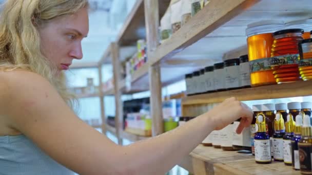 Una Mujer Una Eco Tienda Elige Aceites Aromáticos Cosméticos Naturales — Vídeos de Stock