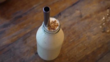 Masadaki bir şişeden beyaz milkshake. Kokteyl pipetli bir şişe süt. Yüksek kalite 4k görüntü