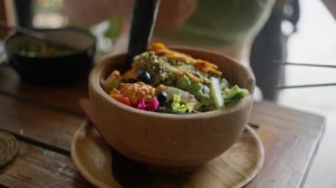 Geleneksel oryantal, Balili, vegan salatası, açık kırsal arka planda ahşap bir tabakta servis ediliyor. Yan görünüş. Yavaş çekim