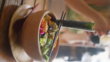 Geleneksel oryantal, Balili, vegan salatası, açık kırsal arka planda ahşap bir tabakta servis ediliyor. Yan görünüş. Ağır çekim. Dikey görünüm