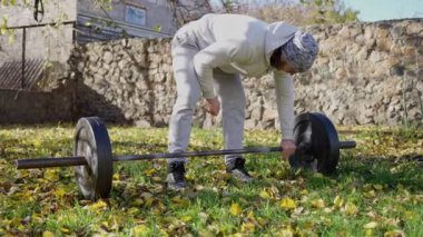 Evin arka bahçesinde halterle antrenman yapan bir sporcunun yakın çekim videosu. Ağır çekim. 4K