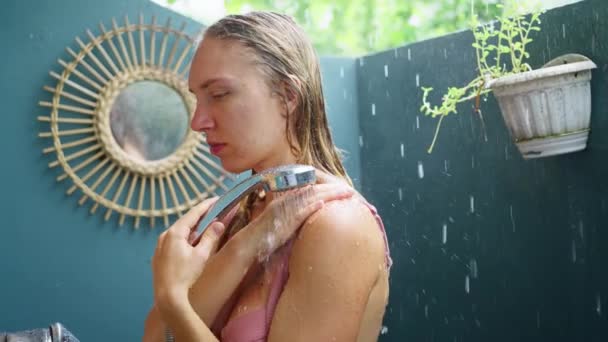 オープンシャワーのスタンド ピンクの水着の少女 雨の外で コントラストシャワーを楽しんで スローモーション 高品質の4K映像 — ストック動画