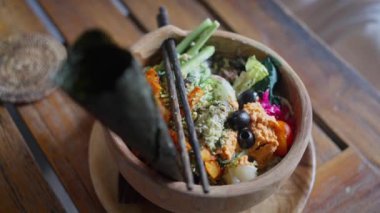 Geleneksel oryantal, Bali yemeği, vegan salatası, ahşap tabakta servis ediliyor. Yan görünüş. Yavaş çekim