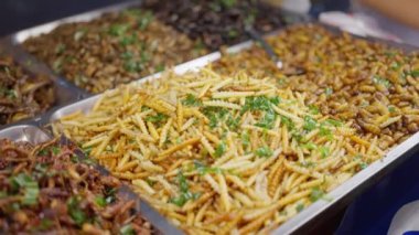 Asya Tayland egzotik yemeklerinde kızarmış böcekler ve akrepler. Bangkok Çin Mahallesi 'nde bir kadın gece pazarında böcek satıyor. Yüksek kalite 4k görüntü