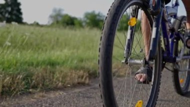 Genç adam gün batımında ormanda tozlu bir patika boyunca bisiklet sürüyor. Bir adam bisiklete biner, sağlıklı bir hayat sürer, seyahat eder. Ağır çekim. 4k görüntü