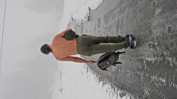 身披赤身裸体的健身男子在冬季的林地里走过一个雪地的山谷 健康和硬化的概念 后视镜垂直录像 慢动作高质量的4K镜头 — 图库视频影像