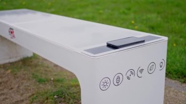 Akıllı bir bankın tepesinde güneş panelleri vardır ve USB cihazlarını ücretsiz şarj edebilir. Üzerinde akıllı telefon olan akıllı bir bank. Ağır çekim. Yüksek kalite 4k görüntü