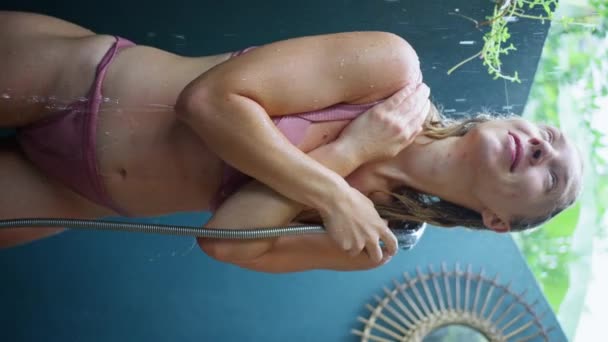 一个赤身裸体的金发女孩 有着美丽的晒黑的身体 在热带花园享受夏日的阵雨 慢动作垂直录像 — 图库视频影像