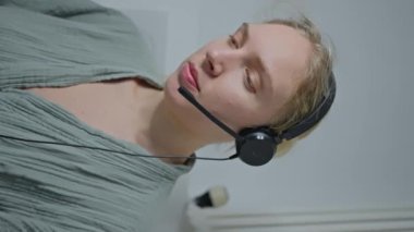 Kulaklık ve dizüstü bilgisayarla tuvalette oturan bir kadın bilişim uzmanı Skype 'ta iş arkadaşlarıyla konuşuyor ve çevrimiçi bir konferansa katılıyor. Dikey video. Yüksek kalite 4k görüntü